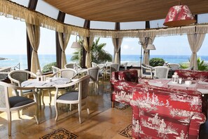 Enjoy ocean views from this dining area with a round table, comfortable seating, and large windows.