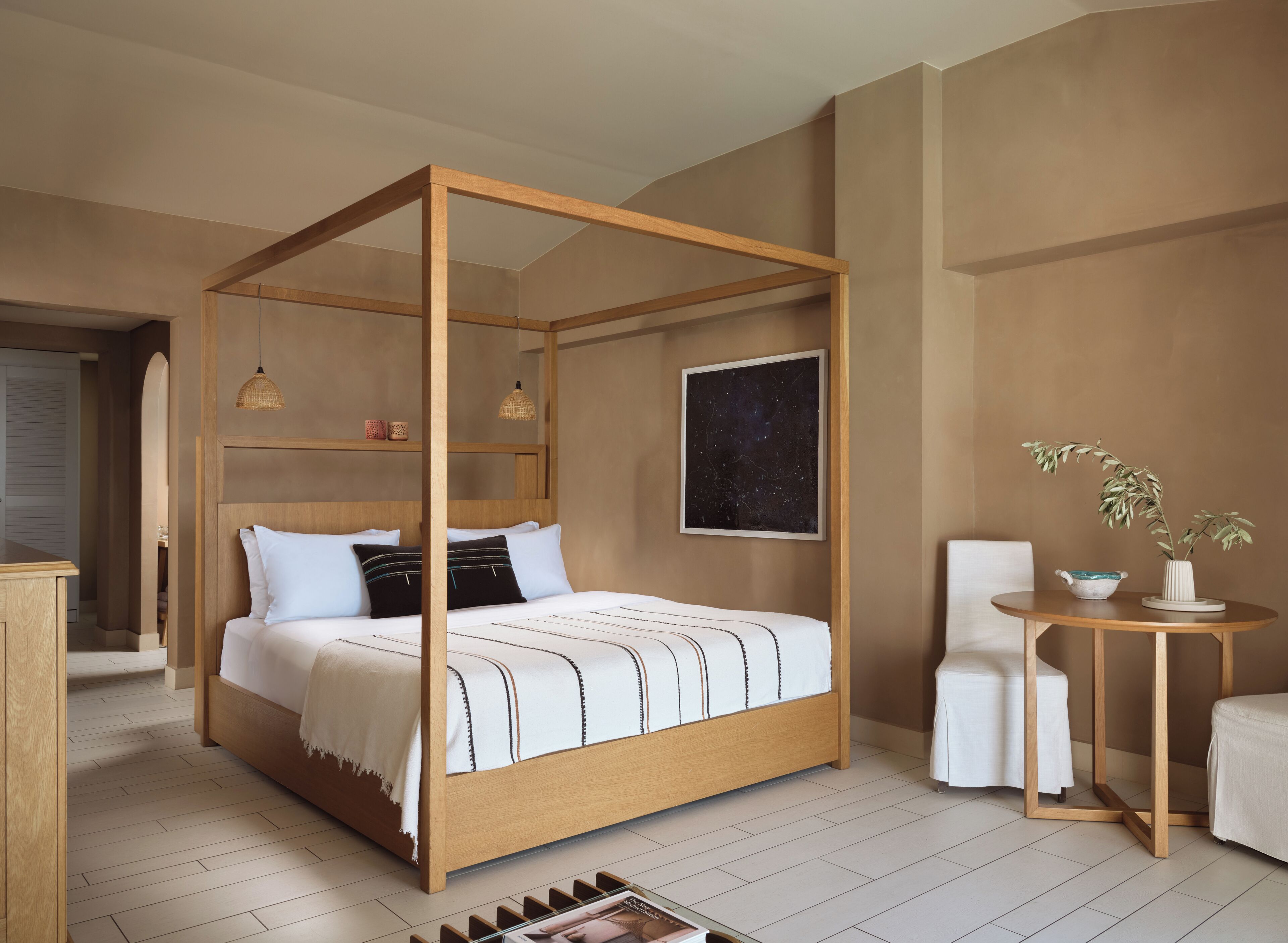 A four-poster bed with a wooden frame, white bedding, and a starry night sky painting on the wall.