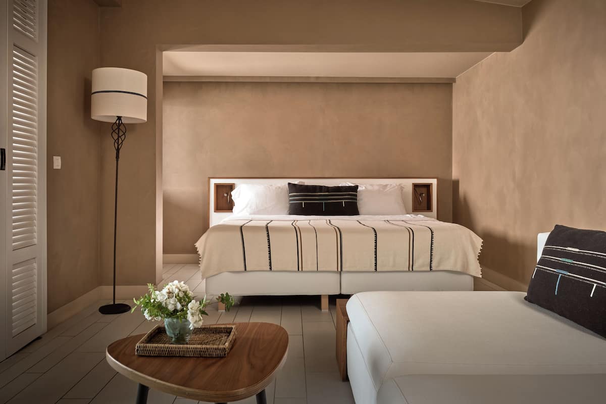 A bedroom with a bed, bedside tables, a floor lamp, and a small table with a vase of flowers.