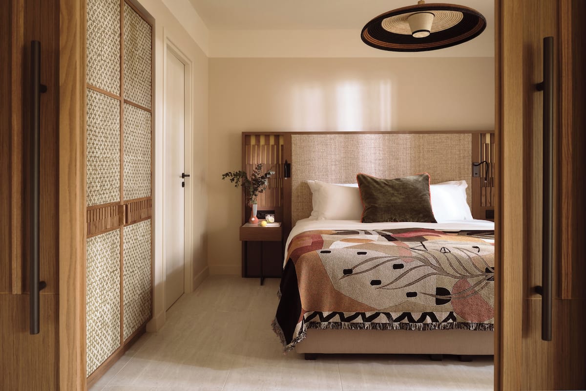 A bedroom with a large bed, a bedside table with a lamp, and a sliding door with a patterned screen.