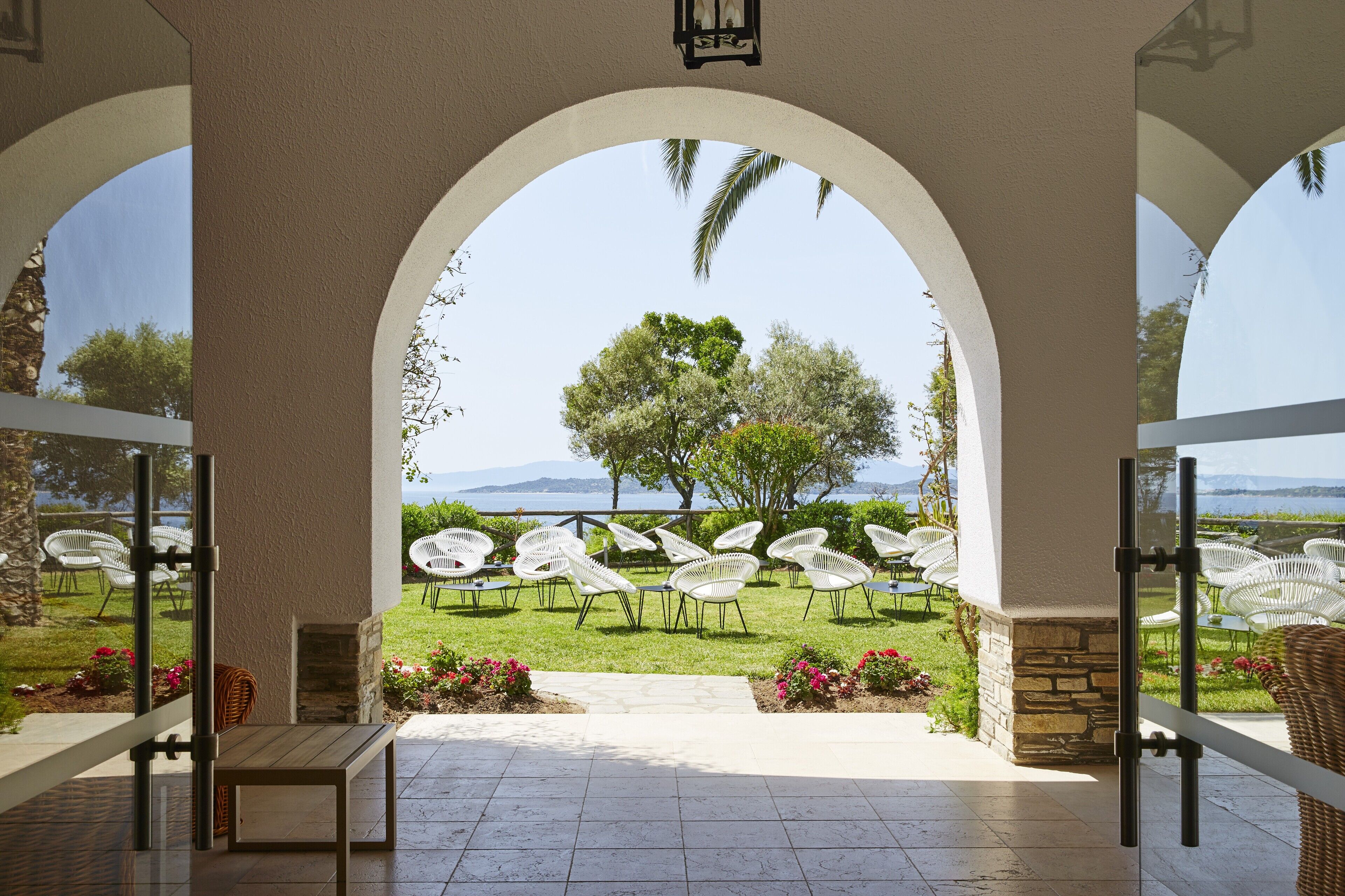 An outdoor patio with white chairs and a view of a tree and mountains.
