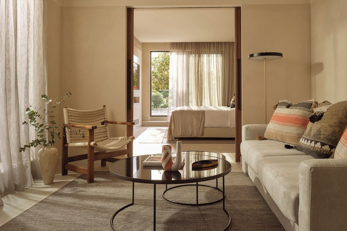 A modern bedroom with a bed, a sofa, a round coffee table, and a chair.