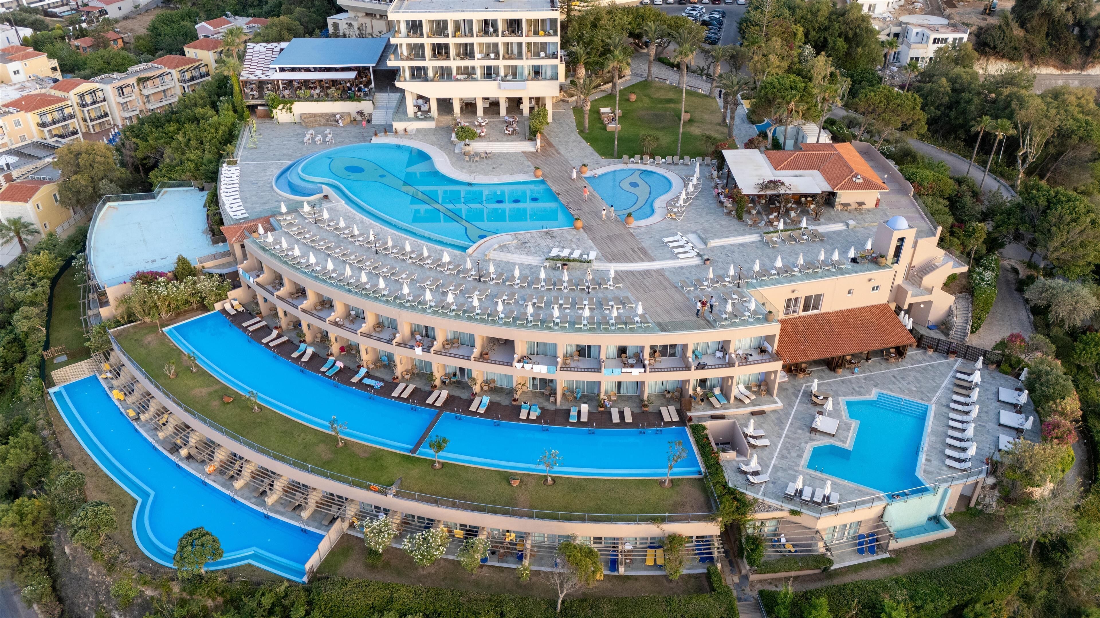 A resort with multiple swimming pools, a rooftop bar, and a large building with balconies.
