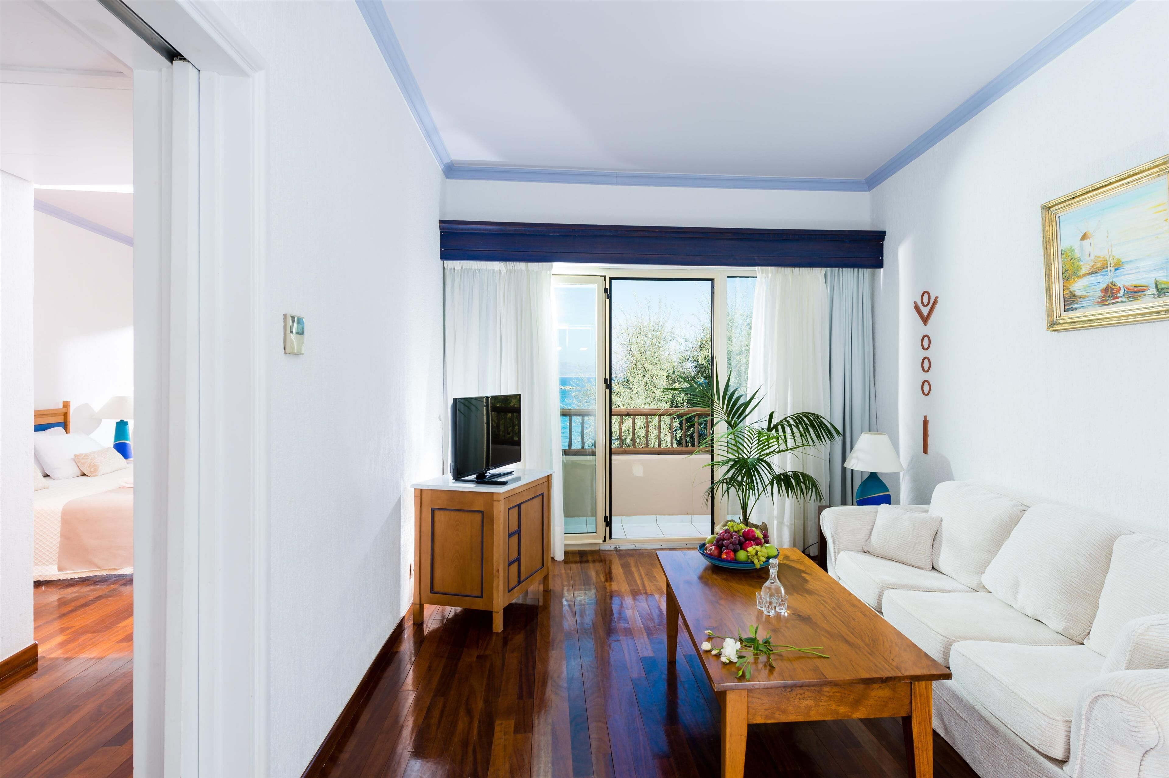 A modern living room with a wooden coffee table, white sofa, and a television on a wooden cabinet.