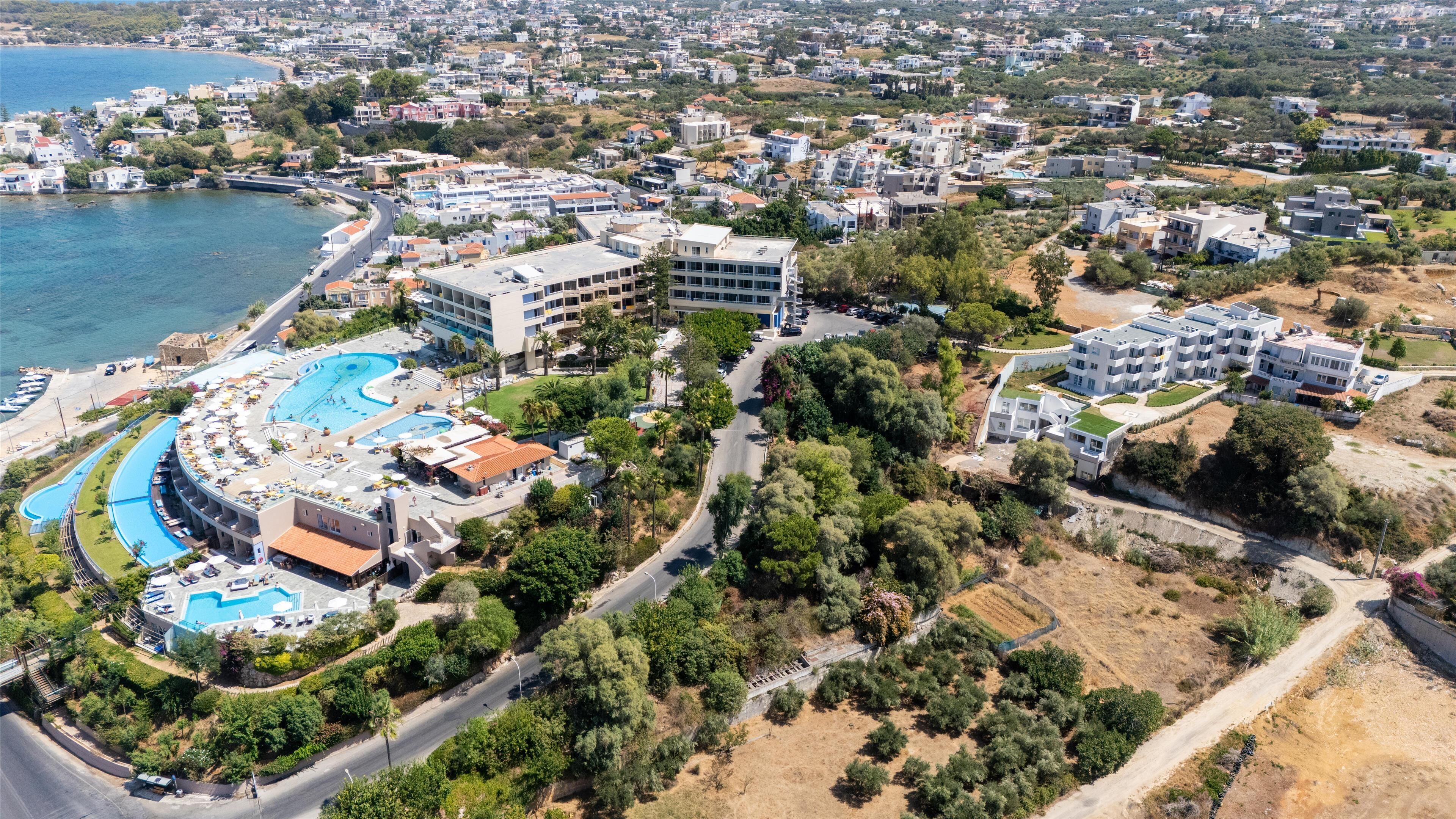Ett flygbildsfoto av en kustort med flera pooler, en central byggnad och omgivande bostadsområden.