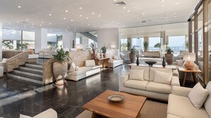A spacious living area with a modern design, featuring a large sofa set, a coffee table, and a staircase leading to an upper level. - Leptos Panorama Hotel (Chania)