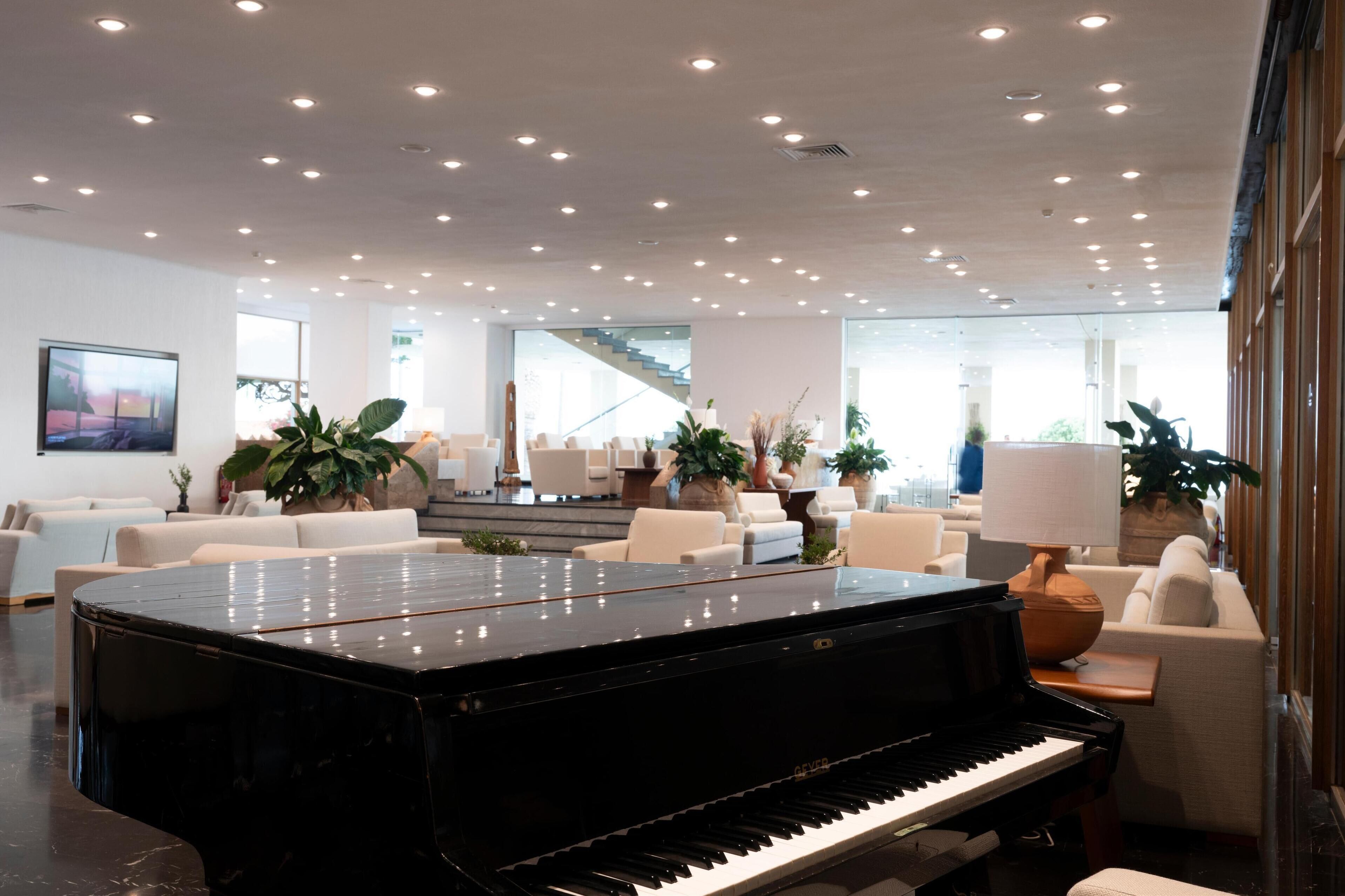 A spacious lobby with a grand piano, comfortable seating, and large windows offering natural light.