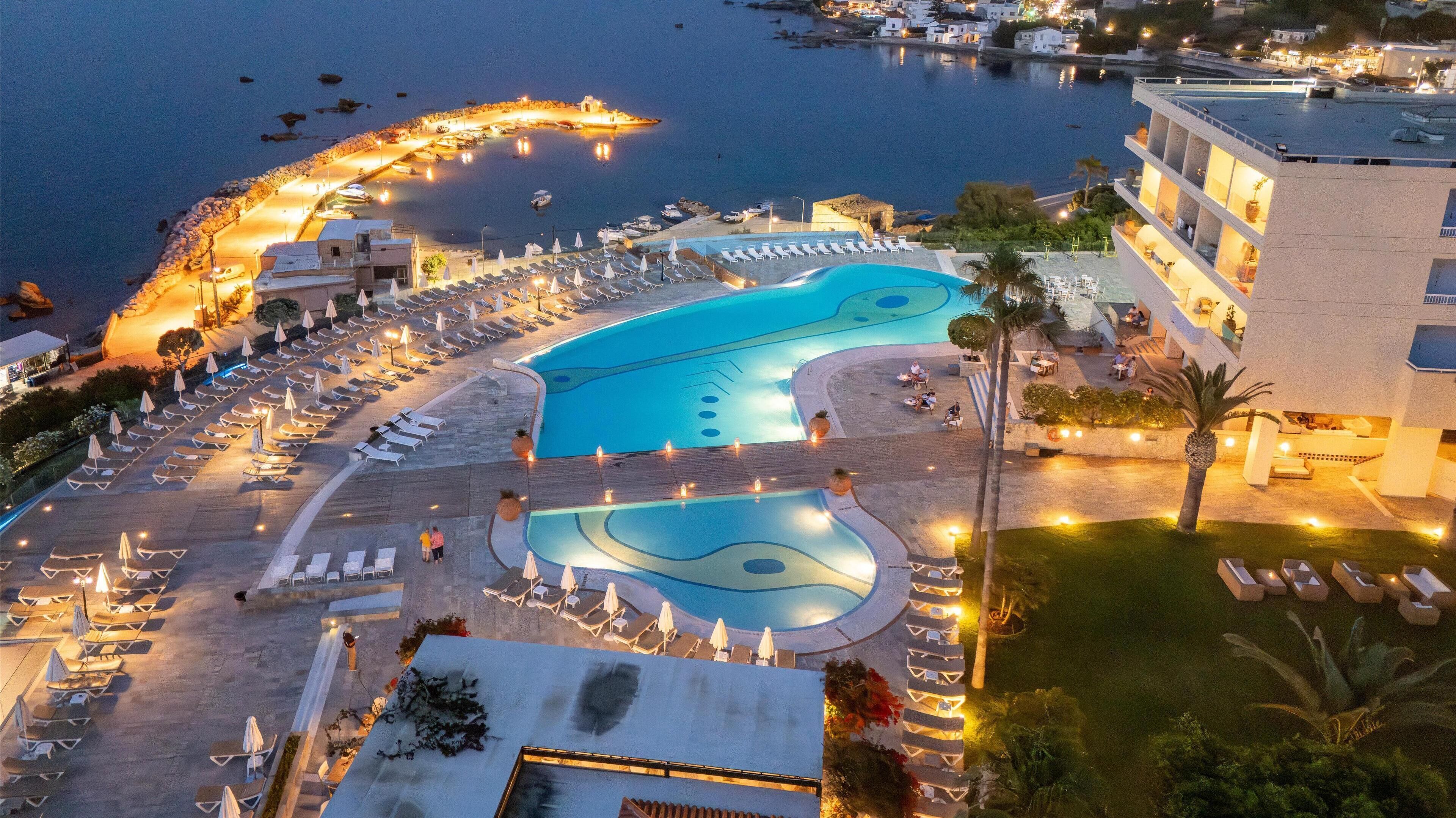 A resort with a large pool, sun loungers, and a marina.
