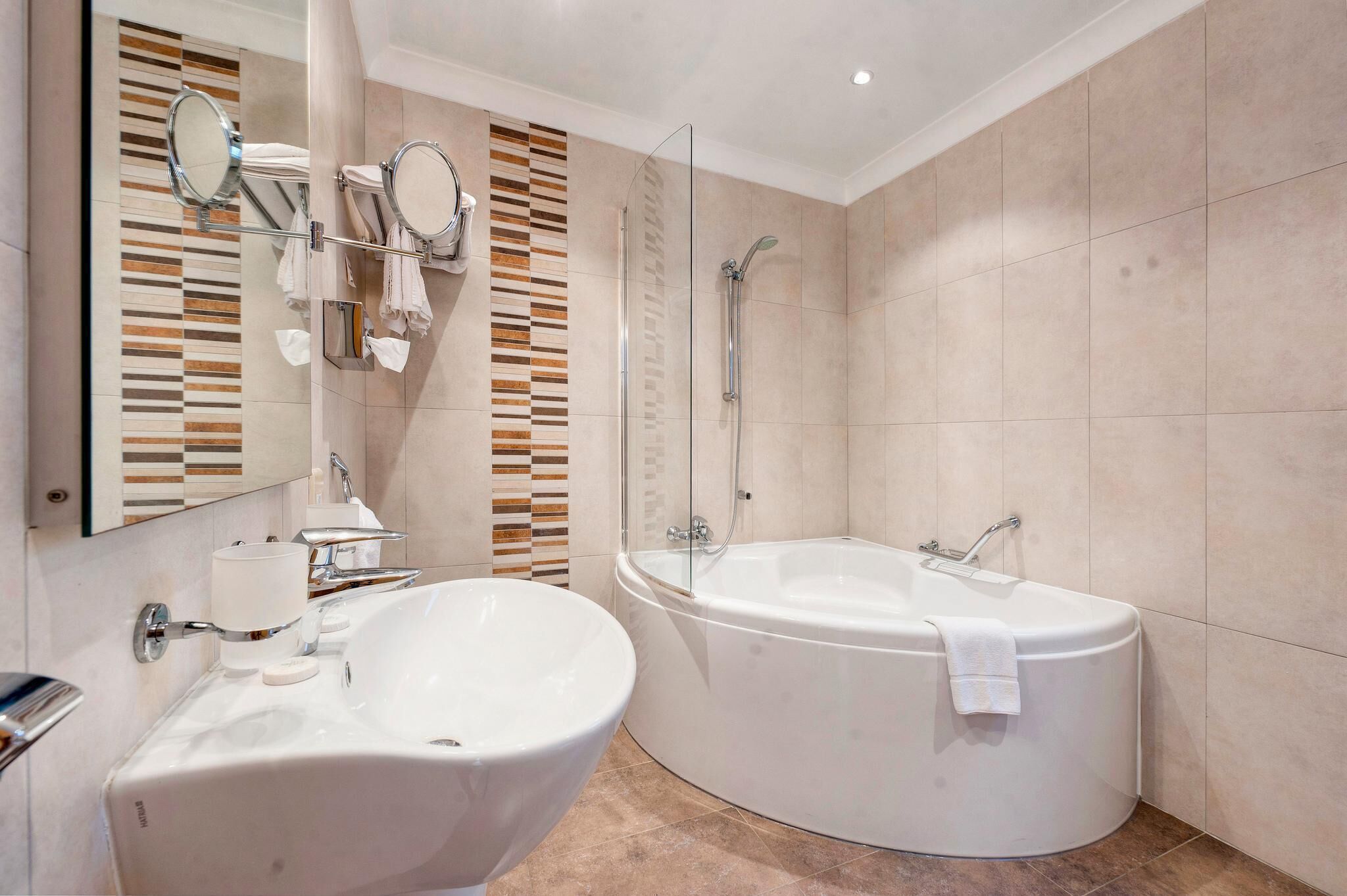 Un baño moderno con una bañera grande, un lavamanos separado y una ducha con mampara de vidrio.