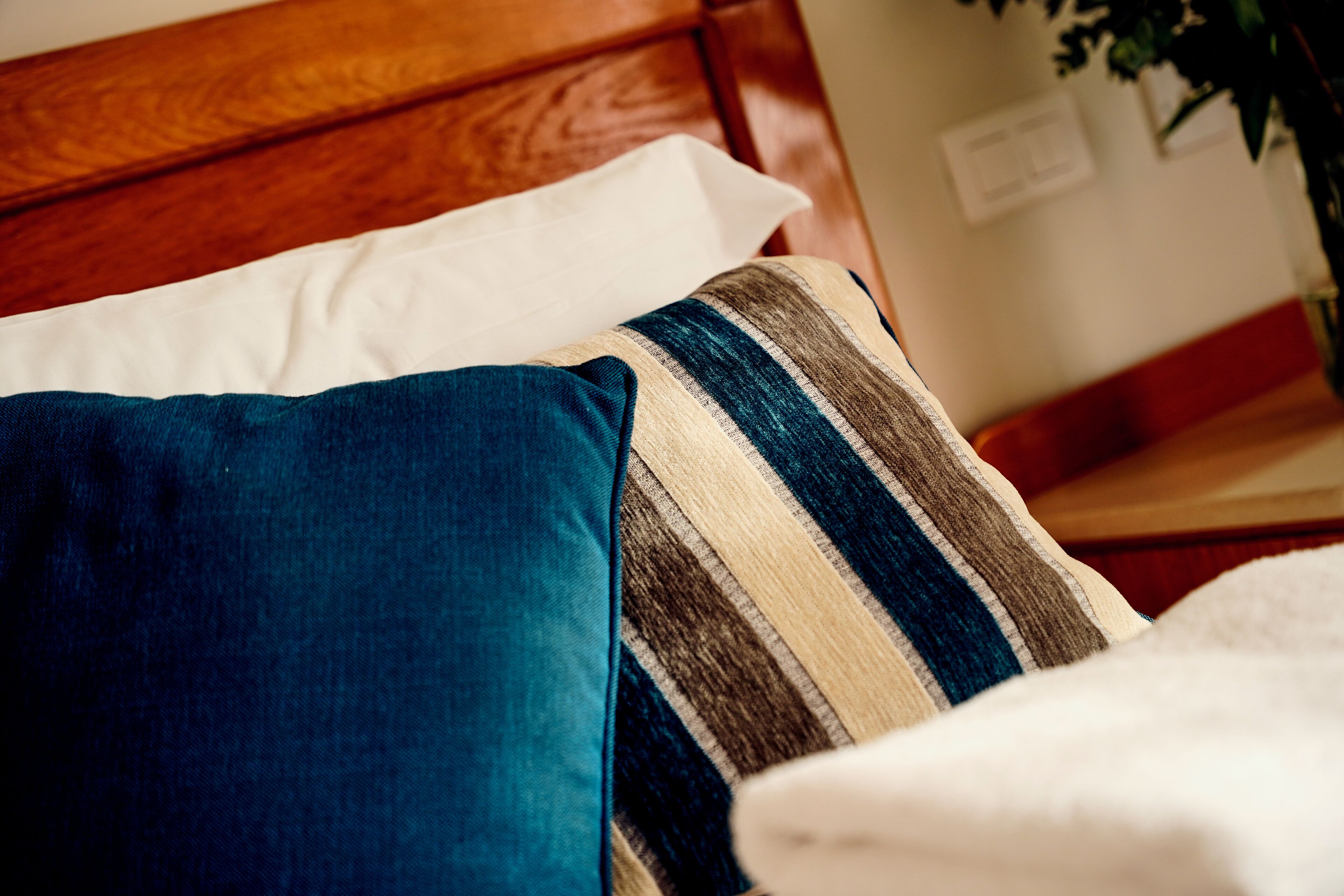 A bed with a wooden headboard, a striped pillow, and a white pillow.