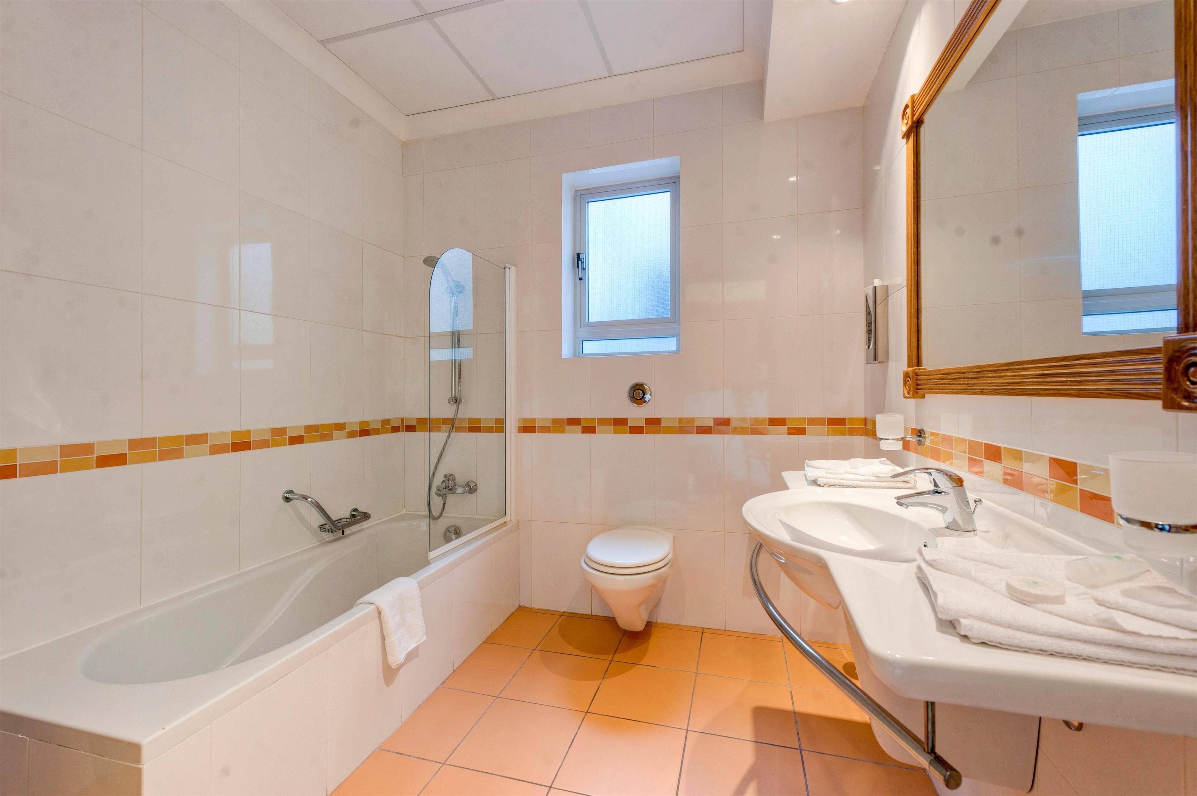 A modern bathroom with a bathtub, toilet, and sink.