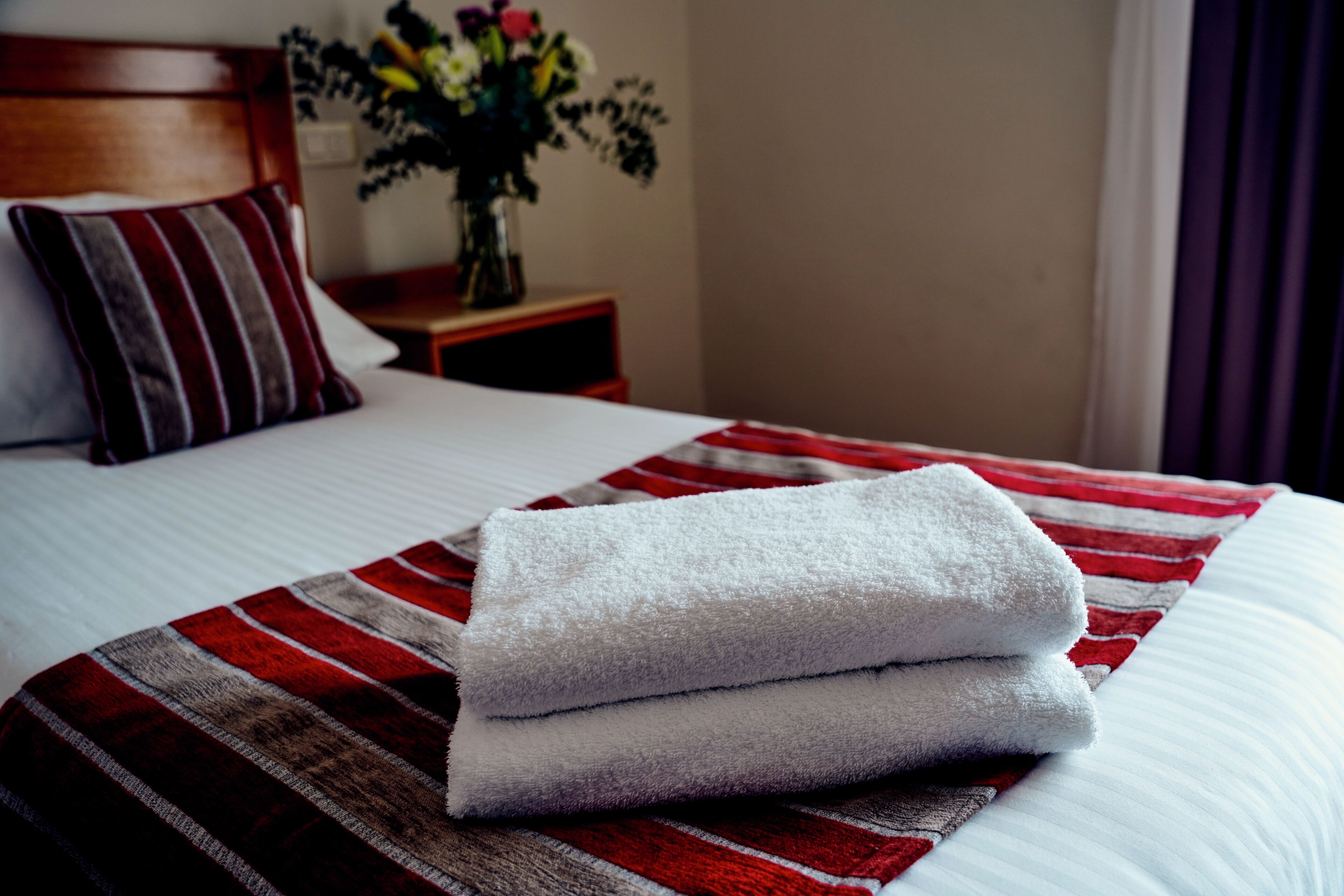 A neatly made bed with a striped blanket and folded white towels.