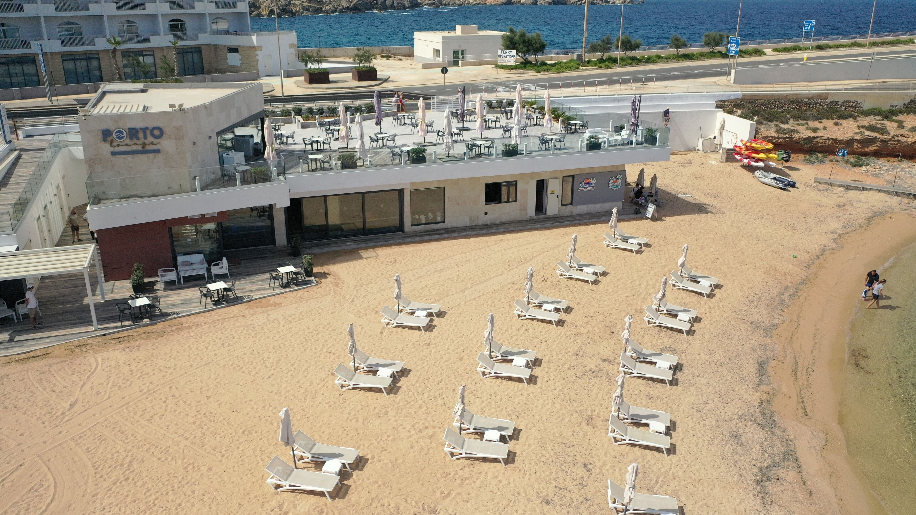 A beachside hotel with outdoor seating and sun loungers.