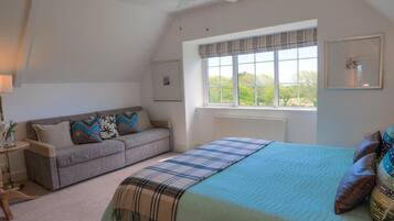 A bedroom with a bed, a window with curtains, a ceiling fan, and a sofa.