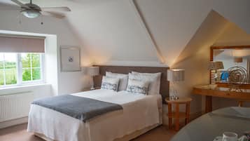 Ein Schlafzimmer mit Bett, Nachttischen, Schreibtisch, Spiegel und Deckenventilator.