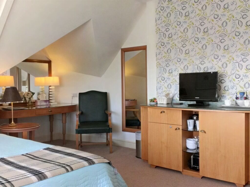 A bedroom with a bed, a desk, a chair, a television, and a wardrobe.
