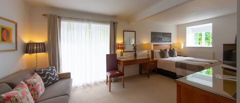 Una habitación de hotel con una cama, un escritorio, una silla, un sofá y un televisor.