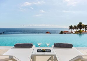 A poolside lounge with two lounge chairs, a tray with two martini glasses and a bowl of olives, and a view of the ocean and palm trees. - Landmar Playa La Arena (Santiago del Teide)