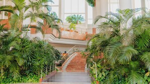 A grand staircase surrounded by lush tropical plants, leading to a balcony with a view of the outdoors. - Landmar Playa La Arena (Santiago del Teide)