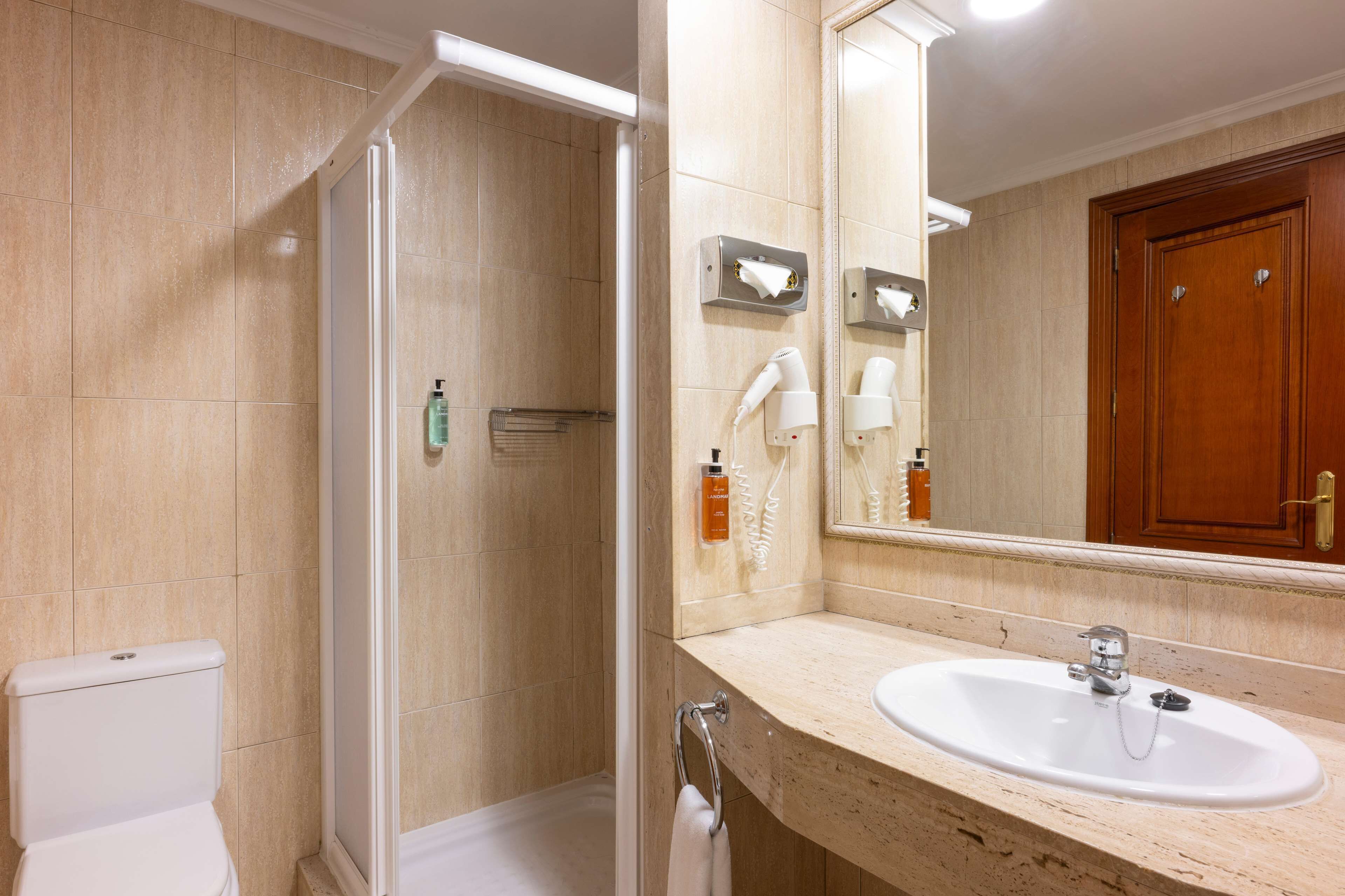 A bathroom with a shower, toilet, sink, and a mirror.