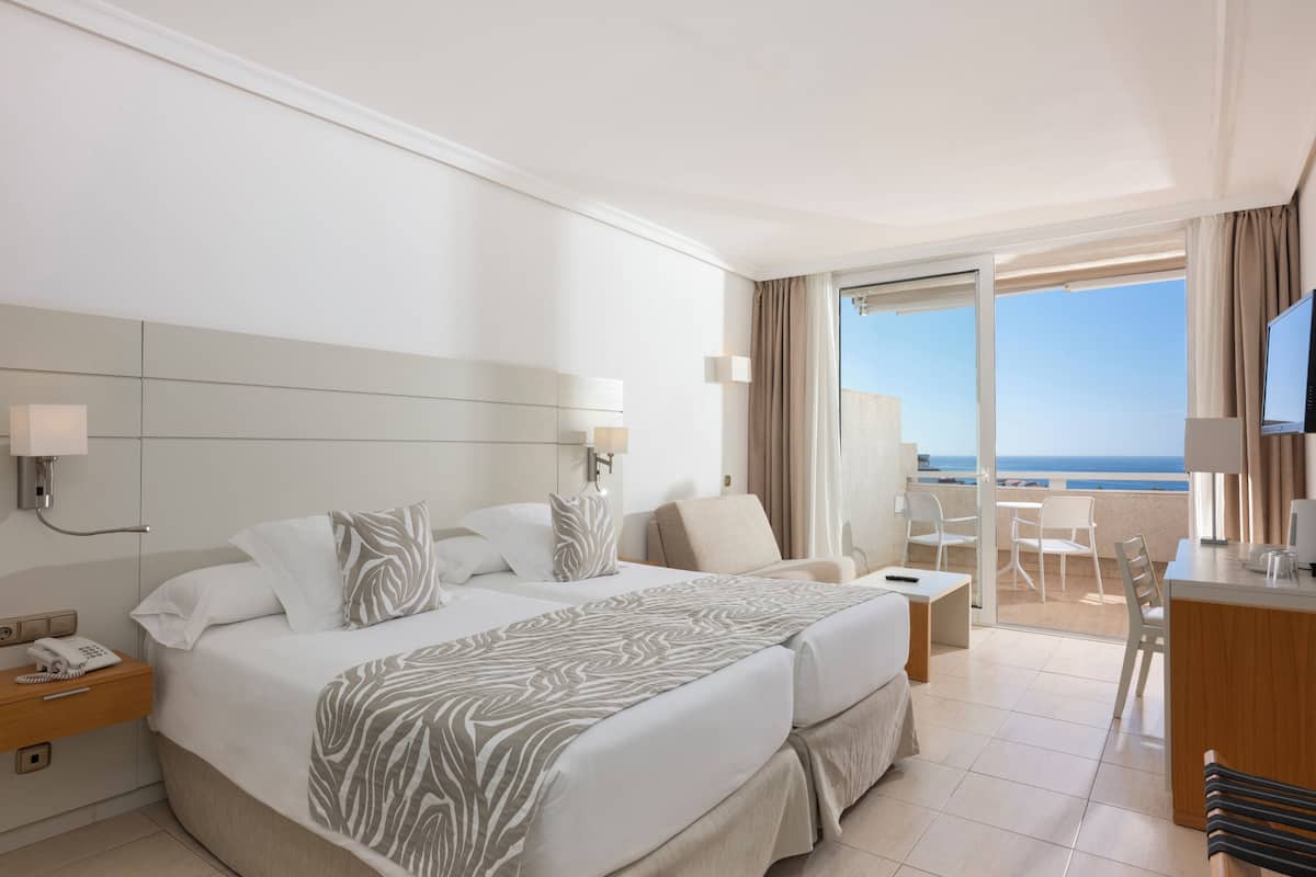 Ein Hotelzimmer mit Bett, Schreibtisch, Stuhl und Meerblick.