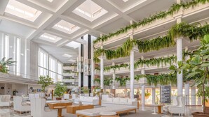 A spacious lobby with a high ceiling, multiple seating areas, and lush vertical gardens. - Landmar Playa La Arena (Santiago del Teide)