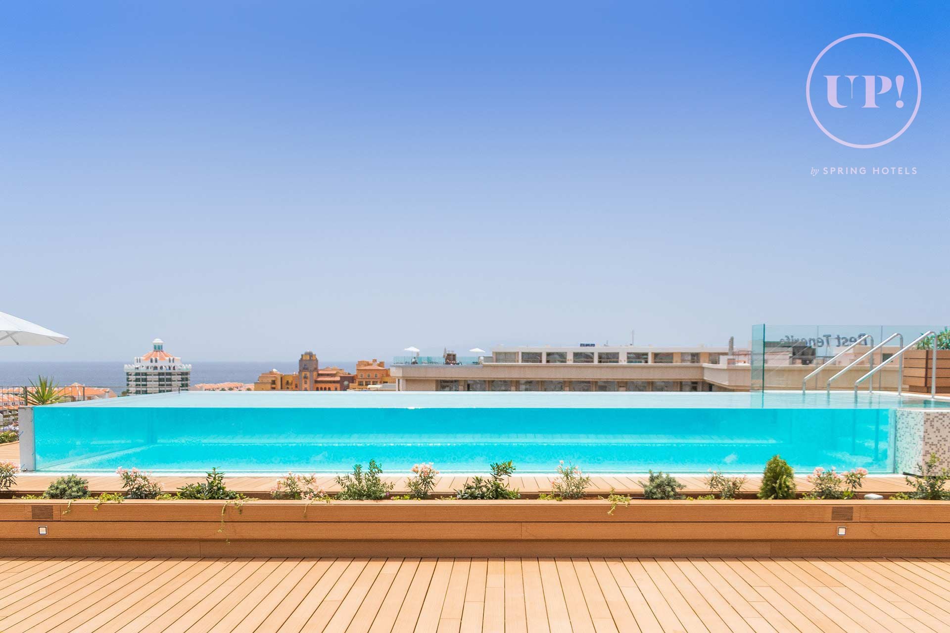 Une piscine avec vue sur l’océan et des bâtiments en arrière-plan.