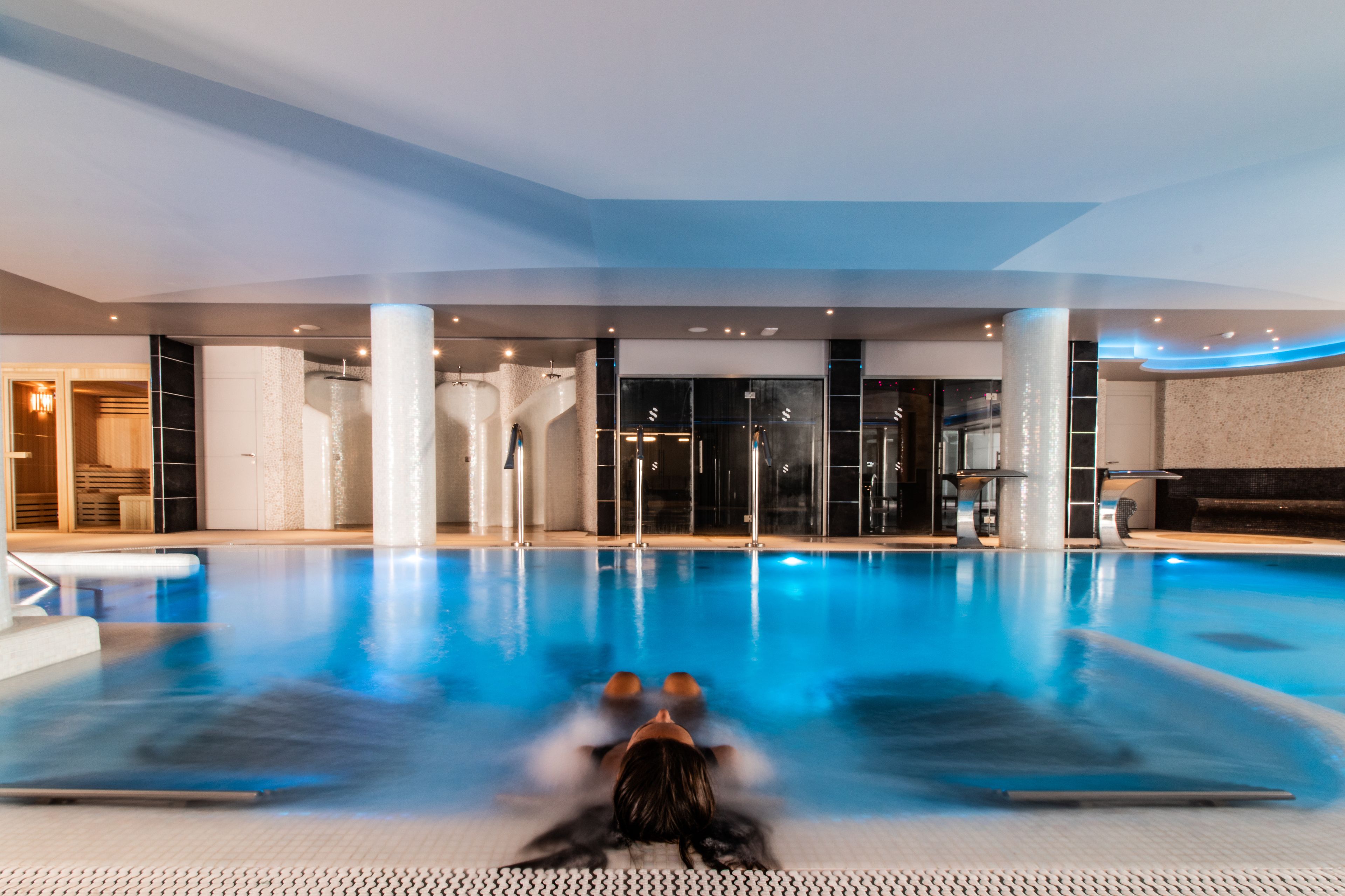 En stor indendørs swimmingpool med en person, der flyder i midten.