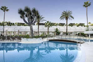 A swimming pool with lounge chairs and palm trees.