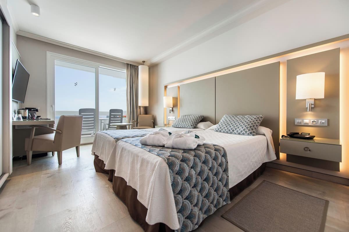 Hotelkamer met een bed, een bureau, een stoel, een televisie en een balkon met uitzicht.