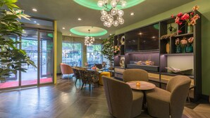 A modern interior with a seating area, a fireplace, and a view of the outdoors. - Leonardo Hotel Antwerp (Antwerp)