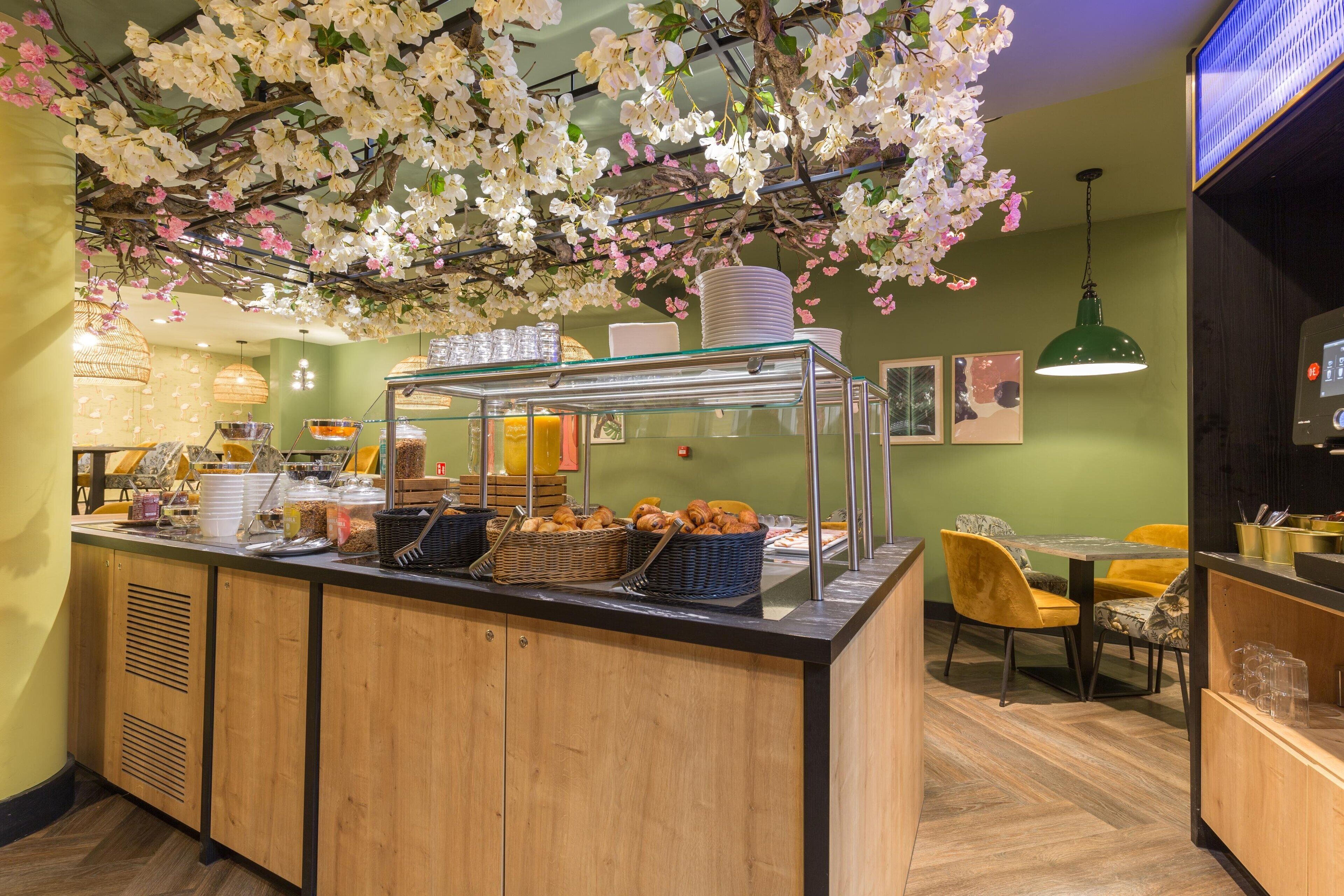 Una barra de desayuno con diversos alimentos y una instalación decorativa de orquídeas encima.