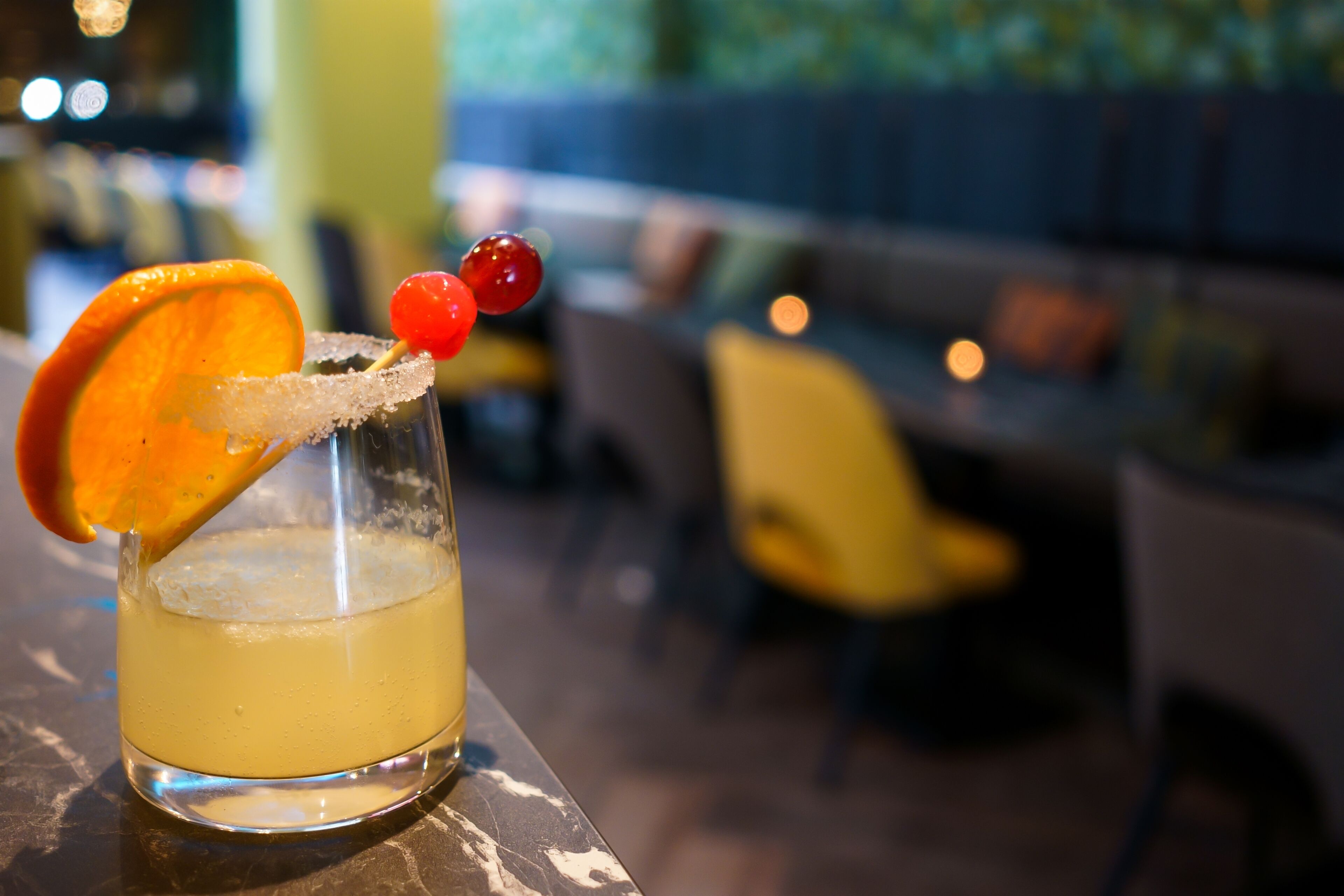 A cocktail with a salted rim and garnishes, served in a glass on a bar counter.