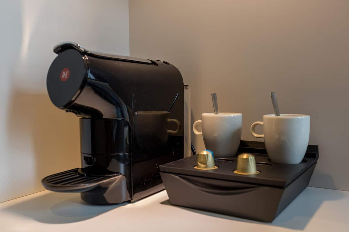 Una máquina de café con dos tazas y dos cucharas sobre una bandeja.