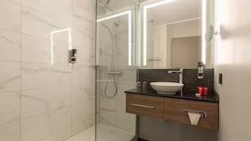 A modern bathroom with a glass-enclosed shower, a sink with a wooden vanity, and a mirror with integrated lighting.