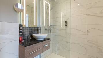A modern bathroom with a marble-tiled shower, a vessel sink, and a wooden vanity.