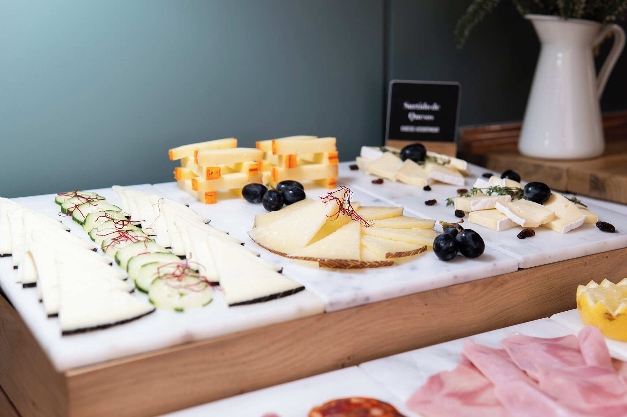 A cheese board with various cheeses, grapes, and herbs.