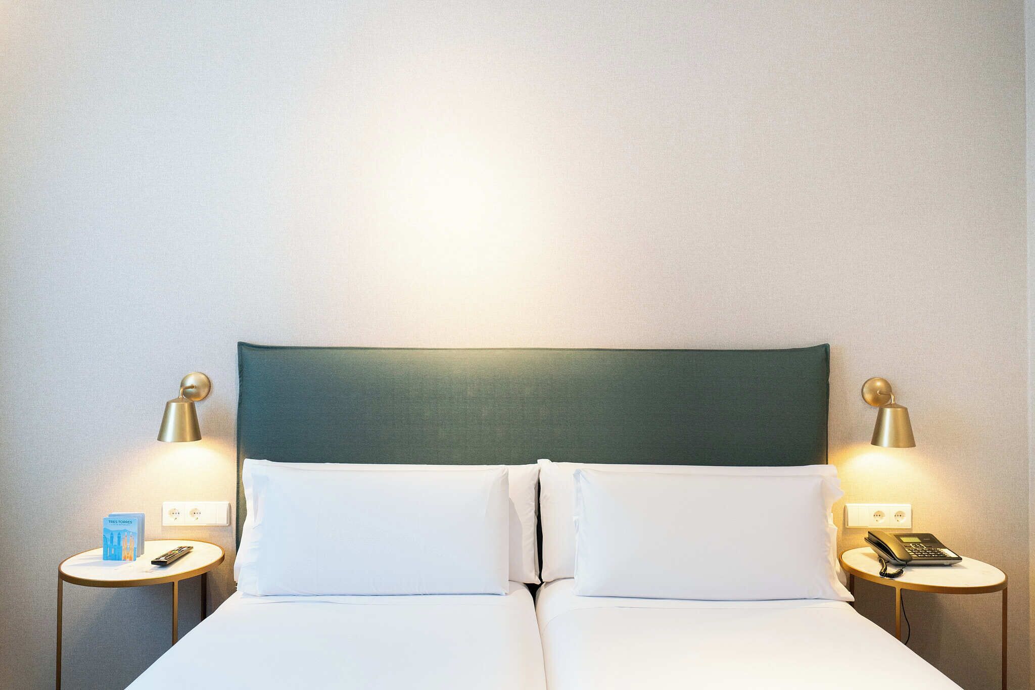Een hotelkamer met een bed, twee nachtkastjes en twee lampen.