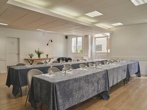 Conference room with a long table, potted plants, and large windows.