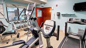 Un gimnasio con máquinas de cardio, mancuernas y una cinta de correr.