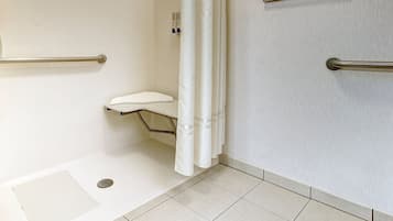Un bagno con doccia, servizi igienici e maniglie di sostegno.