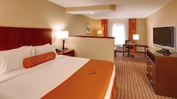 Habitación de hotel con una cama grande, un escritorio con silla, televisor y minibar.