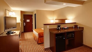 Une chambre d’hôtel comprenant un lit, un bureau avec une télévision, une kitchenette équipée d’un four à micro-ondes et un petit réfrigérateur.