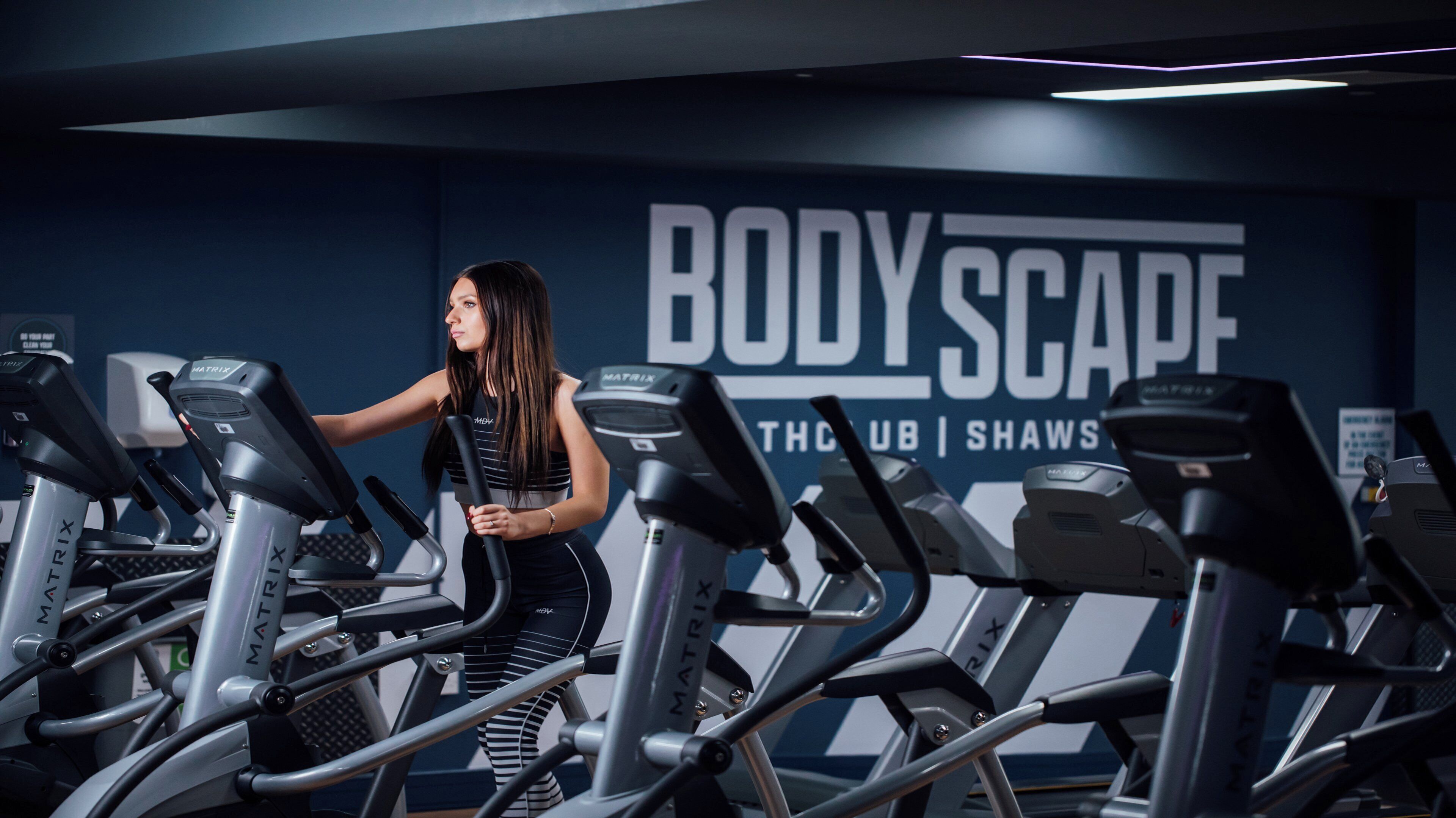 A gym with treadmills and a wall with 'BODY SCAPE' branding.