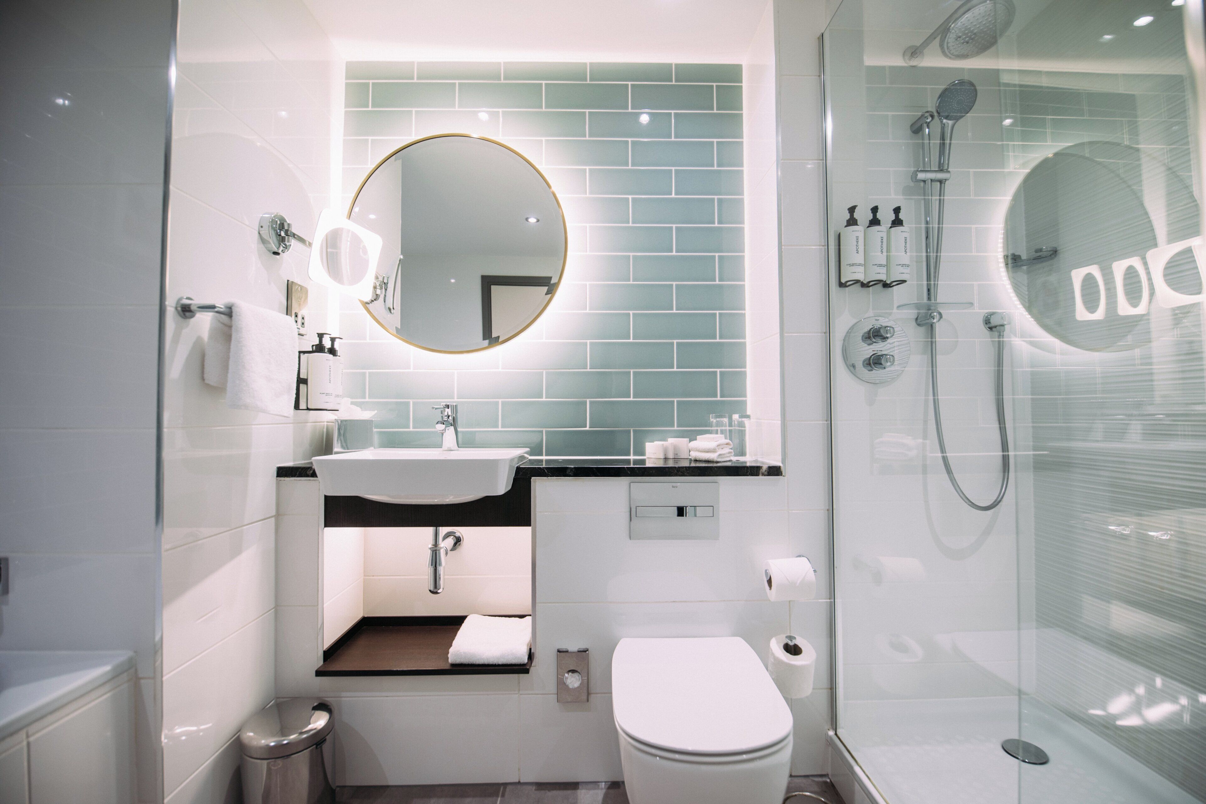 Ein modernes Badezimmer mit Toilette, Waschbecken, Spiegel und Dusche.
