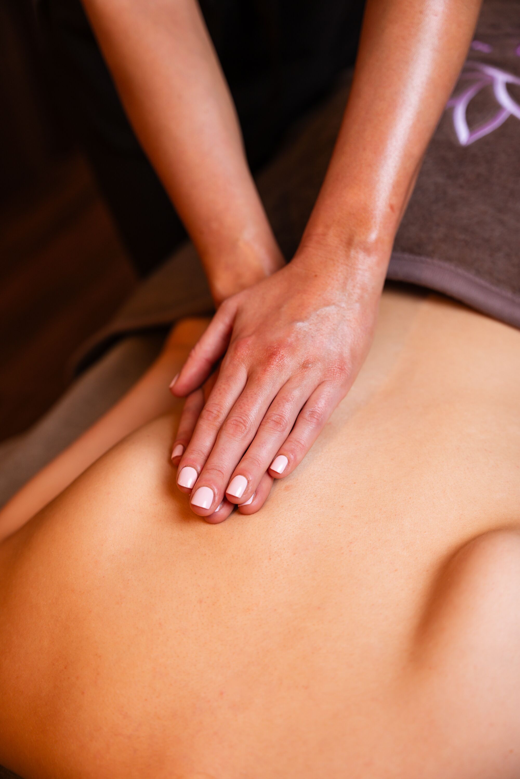 A close-up of hands performing a massage on a person's back.