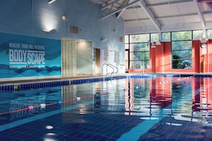 Una piscina interior con señalización clara para diferentes instalaciones, como sauna y salas de vapor, e indicador de profundidad.