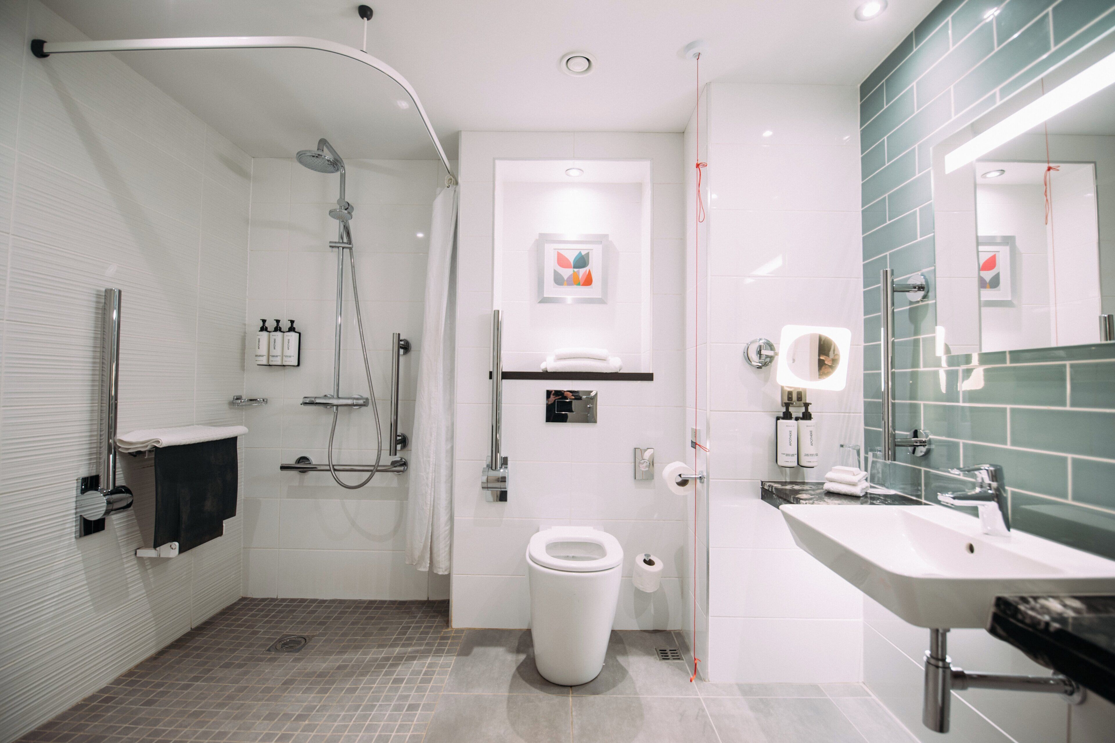 A modern bathroom with a shower, toilet, sink, and a mirror.
