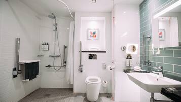 A modern bathroom with a shower, toilet, sink, and a mirror.