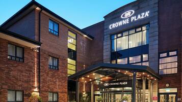 Un hotel de varios pisos con un llamativo letrero de 'Crowne Plaza', ventanas amplias y un área de entrada cubierta.